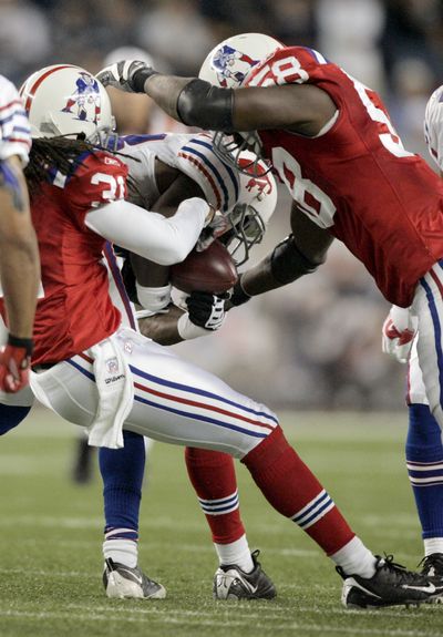 Patriots Brandon Meriweather, left, and Pierre Woods strip the ball from Bills’ Leodis McKelvin in fourth quarter Monday night.  (Associated Press / The Spokesman-Review)