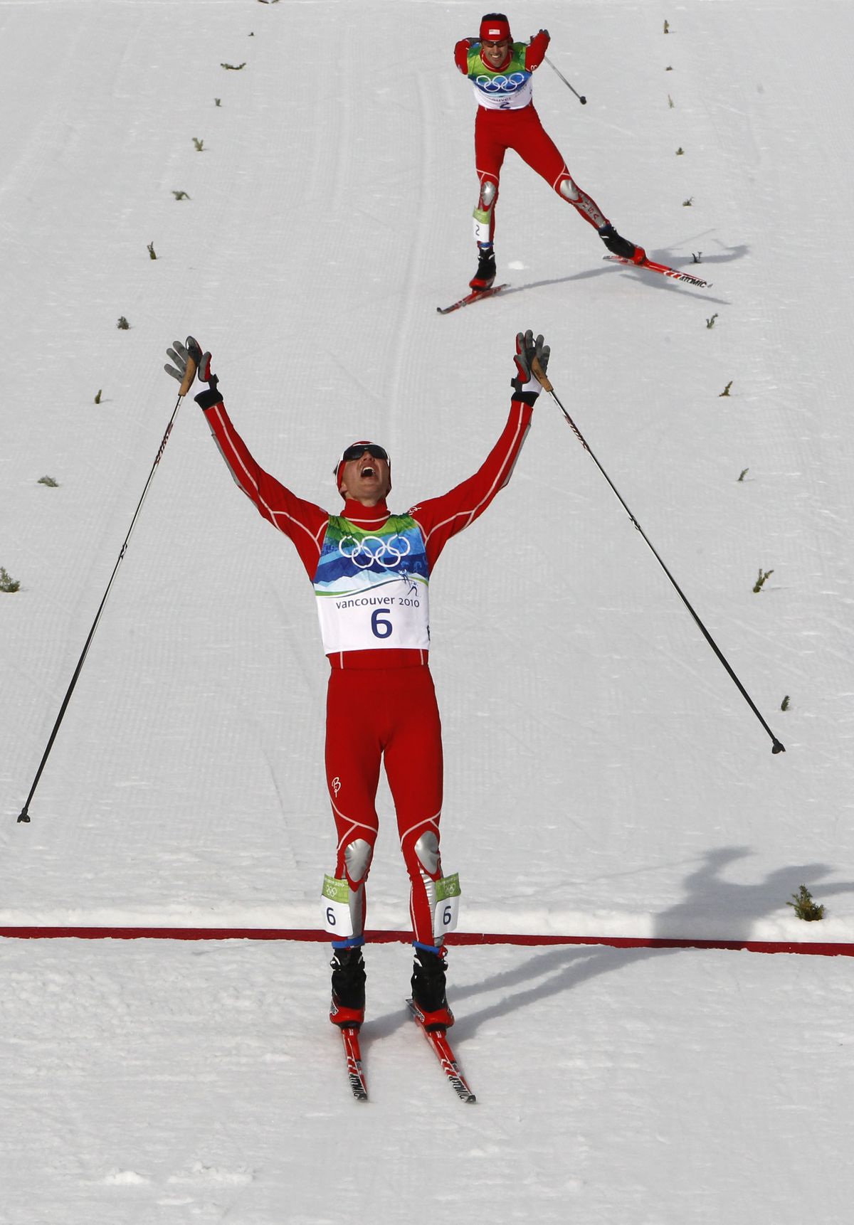 The U.S.’s Bill Demong crosses the finish line to win the gold medal as teammate Johnny Spillane skis to silver in the Men’s Nordic combined individual large hill event.  (Associated Press)