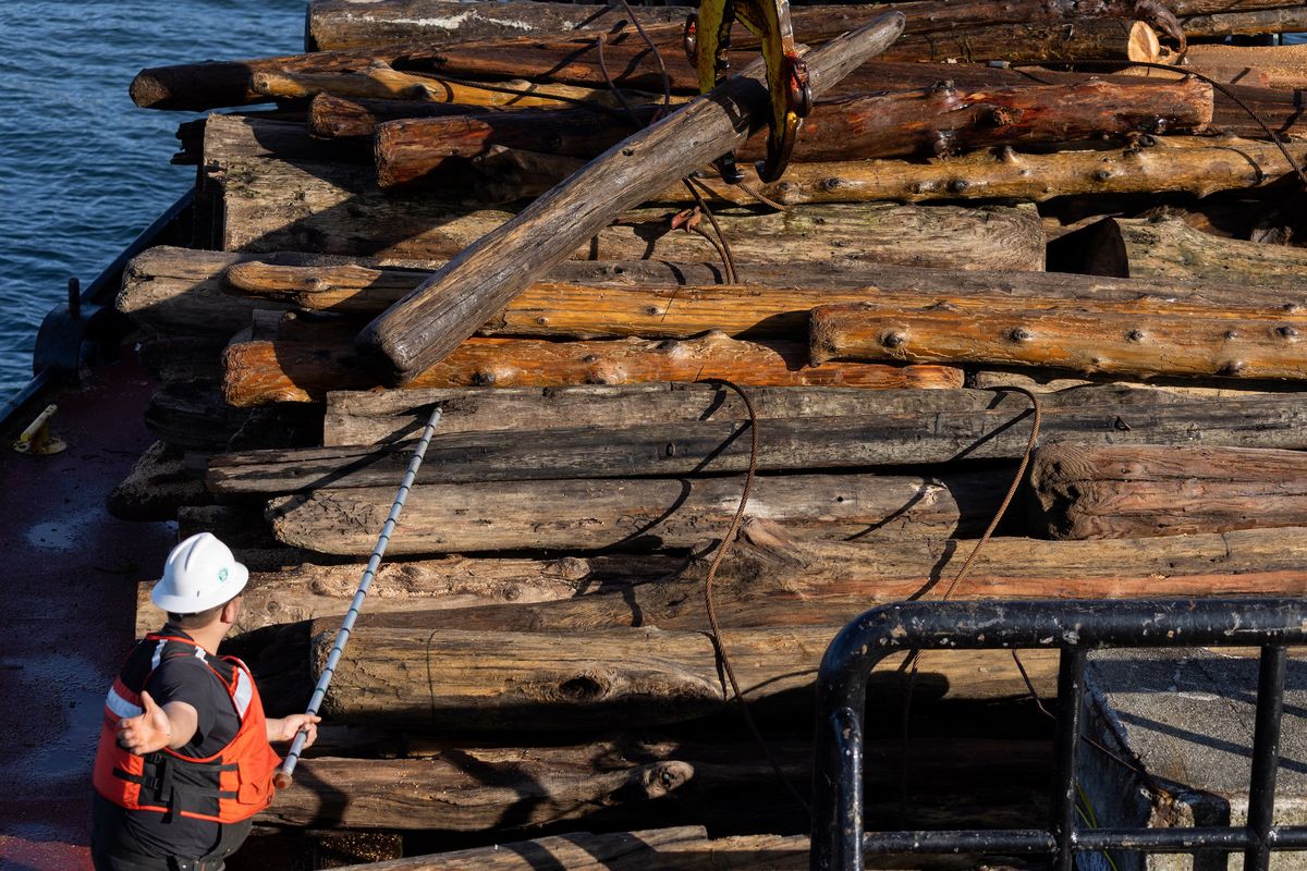 Using a pike pole, small craft operator Silad On hand signals the crane operator as a log is brought aboard the M/V Puget on Jan. 10 as the U.S. Army Corps of Engineers debris recovery vessel goes out on Puget Sound.  (Ken Lambert/The Seattle Times/TNS)