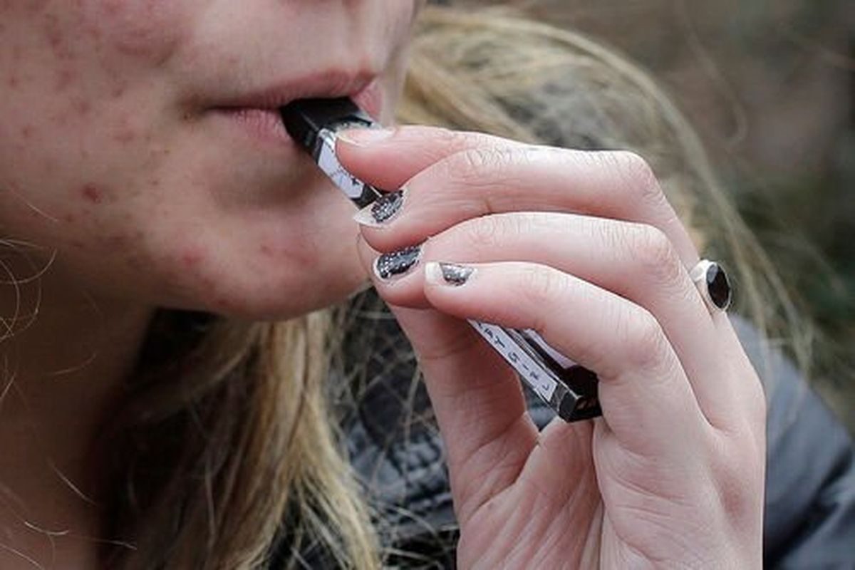 A 15-year-old high school student uses a vaping device near a school campus in Massachusetts. Spokane Public Schools has joined a lawsuit seeking money from vape company Juul.  (Steven Senne)