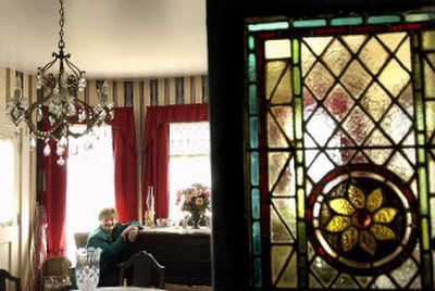 
Lory Miller  is framed in her North Side dining room, complete with antiques and a circa 1800s door from a church in England. Below, pillars and plants provide a welcome scene for the Miller home. 
 (Brian Plonka / The Spokesman-Review)