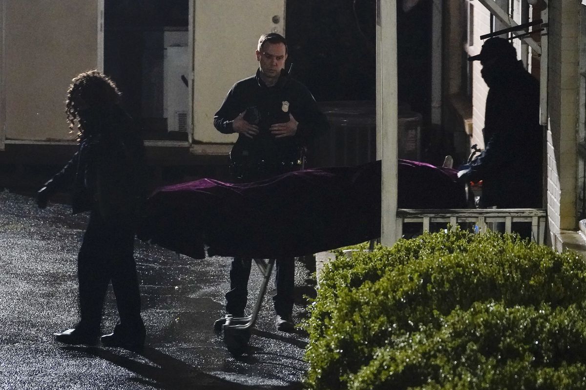A police officer watches as a body is taken from the Gold Spa massage parlor after a shooting, late Tuesday, March 16, 2021, in Atlanta. Shootings at two massage parlors in Atlanta and one in the suburbs left multiple people dead, many of them women of Asian descent, authorities said. A 21-year-old man suspected in the shootings was taken into custody in southwest Georgia hours later after a manhunt, police said.  (Brynn Anderson)