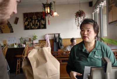 
Cao Lan  helps a customer with a takeout order at China Cafe. The Vietnamese refugee escaped to the United States and made a new life in Spokane. 
 (Holly Pickett / The Spokesman-Review)