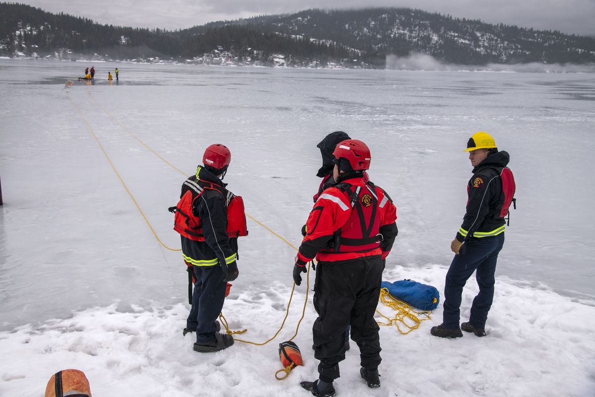 Firefighters with Spokane Valley Fire wait and hold safety lines for other firefighters taking ice rescue training on the shores of Newman Lake Wednesday, Jan. 12, 2022.  (Jesse Tinsley/The Spokesman-Review)