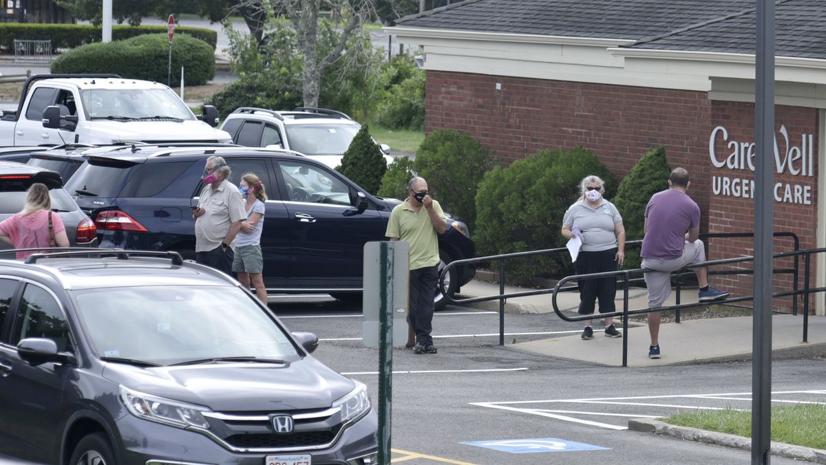 The parking lot is filled with cars at Patriot Square as patients queue up outside the Carewell Urgent Care for a COVID-19 test, Wednesday, Aug. 5, 2020, in Dennis, Mass.  (Steve Heaslip)