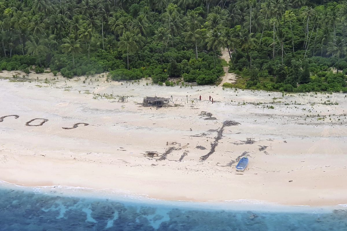 In this photo provided by the Australian Defence Force, three men stand the beach on Pikelot Island in the Federated States of Micronesia Sunday, Aug. 2, 2020, where they are found safe and healthy after missing for three days. The men were missing in the Micronesia archipelago east of the Philippines for nearly three days when their "SOS" sign was spotted by searchers on Australian and U.S. aircraft, the Australian defense department said.  (HOGP)
