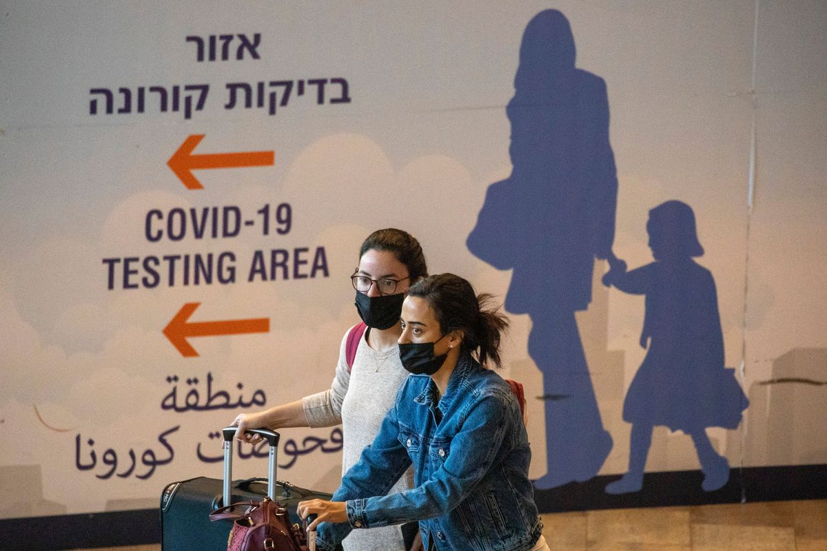 Travelers wearing protective face masks arrive at Ben Gurion Airport near Tel Aviv, Israel, Sunday, Nov. 28, 2021. Israel on Sunday approved barring entry to foreign nationals and the use of controversial technology for contact tracing as part of its efforts to clamp down on a new coronavirus variant.  (Ariel Schalit)
