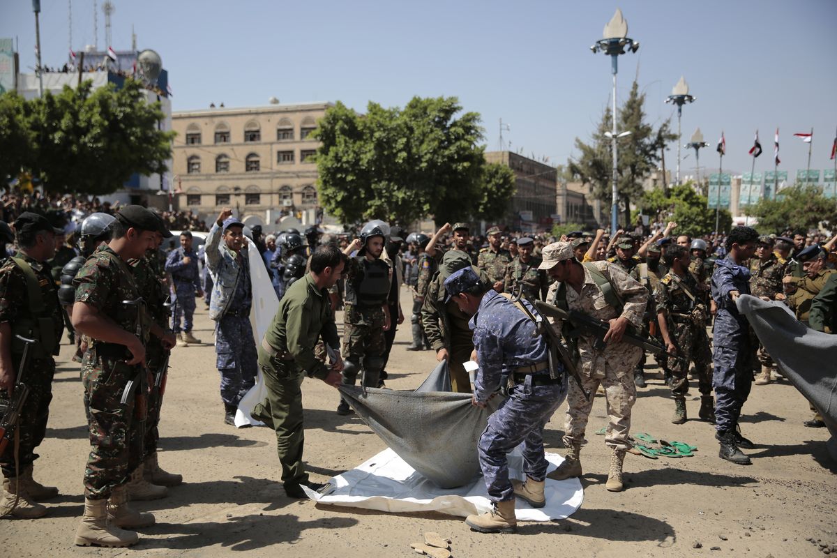 Policemen carry the body of a man, convicted of involvement in the killing of a senior Houthi official Saleh al-Samad, after his execution at Tahrir Square in Sanaa, Yemen Saturday, Sept. 18, 2021. Yemen