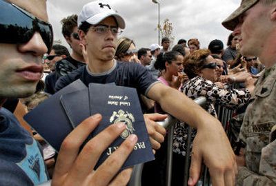 
American citizens show their families' passports to Marines on Wednesday as they wait behind barricades near the U.S. embassy north of Beirut, Lebanon, for their names to be called in order to be processed for evacuation. 
 (Associated Press / The Spokesman-Review)