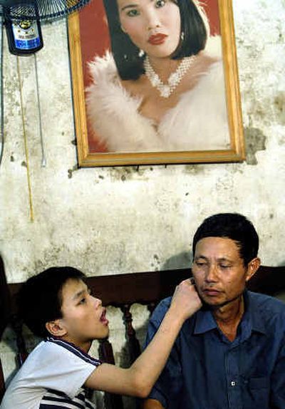 
Nguyen Quang Trung, 17, touches the face of his father, Nguyen Van Quy, 49, who talks about the effects of Agent Orange he was exposed to during the Vietnam War, at his house in Hai Phong, Vietnam last July. The elder Nguyen, who also has a daughter, believes his children's birth defects were caused by Agent Orange that he was exposed to during the Vietnam war. 
 (Associated Press / The Spokesman-Review)