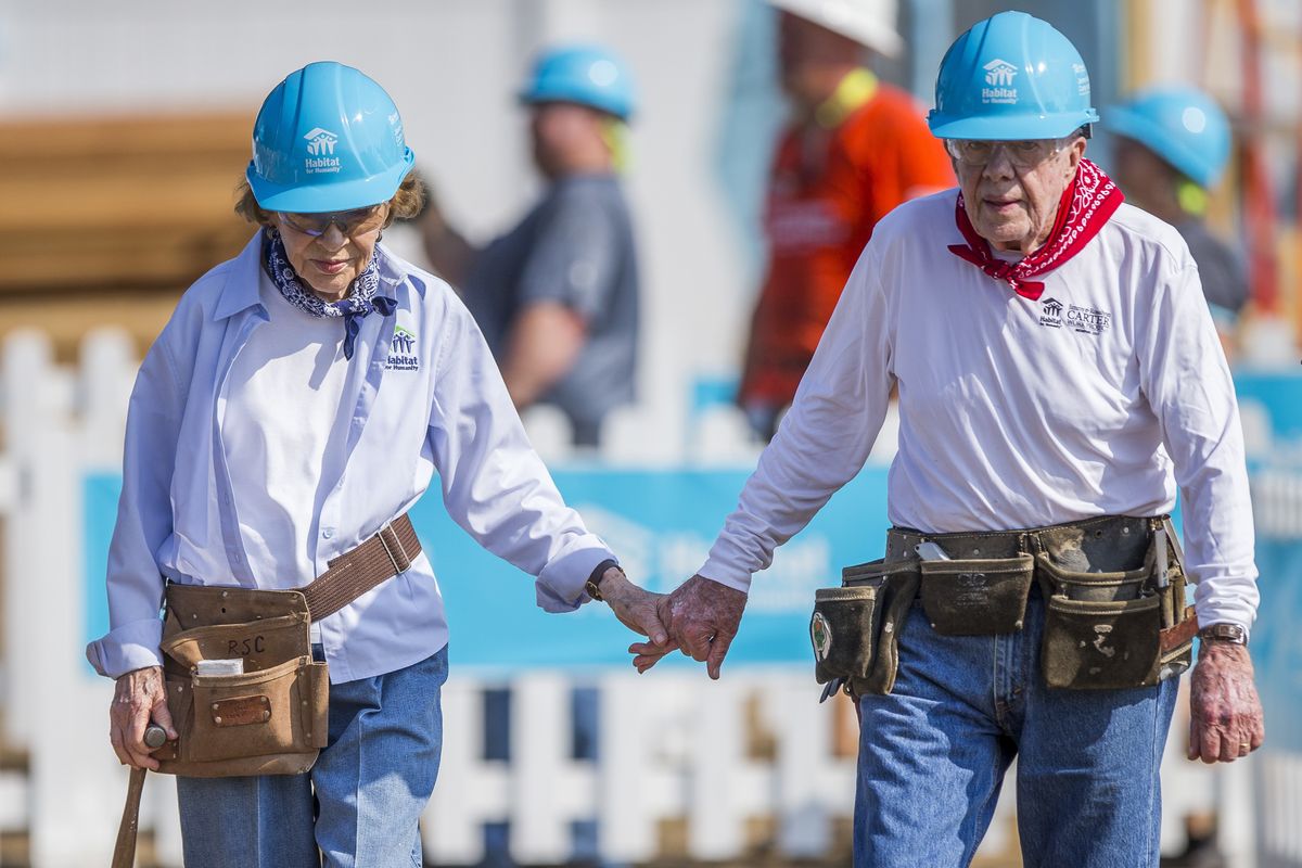 In this Aug. 27, 2018 photo former President Jimmy Carter holds hands with his wife, former first lady Rosalynn Carter, as they work with other volunteers on site during the first day of the weeklong Jimmy & Rosalynn Carter Work Project, their 35th work project with Habitat for Humanity in Mishawaka, Ind. Jimmy Carter and his wife Rosalynn celebrate their 75th anniversary this week on Thursday, July 7, 2021.  (Robert Franklin)