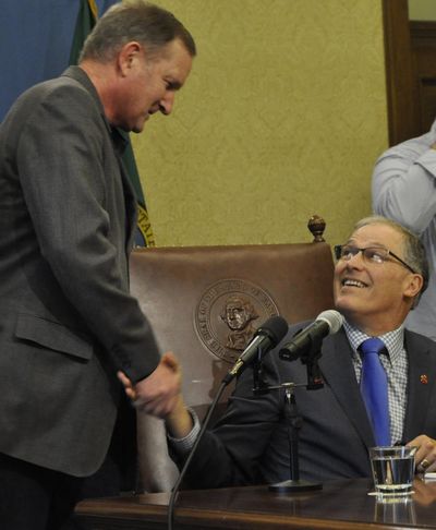 OLYMPIA – Gov. Jay Inslee congratulates Rep. Jeff Holy, R-Cheney, the sponsor of a bill that reforms the way legal financial obligations are handled by Washington courts. Inslee signed the bill into law Tuesday. (Jim Camden / The Spokesman-Review)