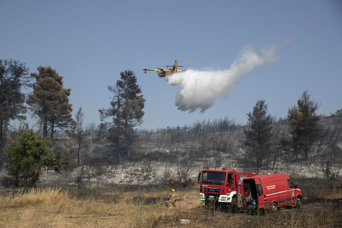 A firefighting airplane drops water during a forest fire at Dionysos northern suburb of Athens, on Tuesday, July 27, 2021. Greek authorities have evacuated several areas north of Athens as a wildfire swept through a hillside forest and threatened homes despite a large operation mounted by firefighters.  (Yorgos Karahalis)