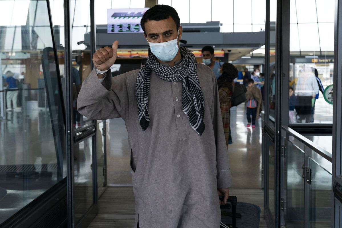 Families evacuated from Kabul, Afghanistan, walk through the terminal before boarding a bus after they arrived at Washington Dulles International Airport, in Chantilly, Va., on Friday, Aug. 27, 2021.  (Jose Luis Magana)