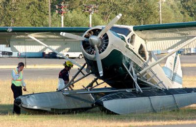
Investigators look over a float plane involved in a midair collision Thursday in Renton, Wash. The pontoons on the plane were bent by the collision before the plane landed in the grass between the runway and the taxiway. 
 (Associated Press / The Spokesman-Review)