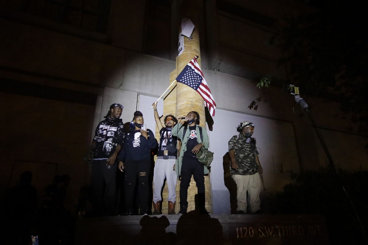 A group of demonstrators talks to the crowd during a Black Lives Matter protest at the Mark O. Hatfield United States Courthouse Thursday, July 23, 2020, in Portland, Ore.  (Marcio Jose Sanchez)