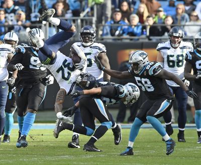Seahawks running back Chris Carson somersaults over Panthers’ Eric Reid during the second half of Sunday’s game in Charlotte. (Mike McCarn / Associated Press)