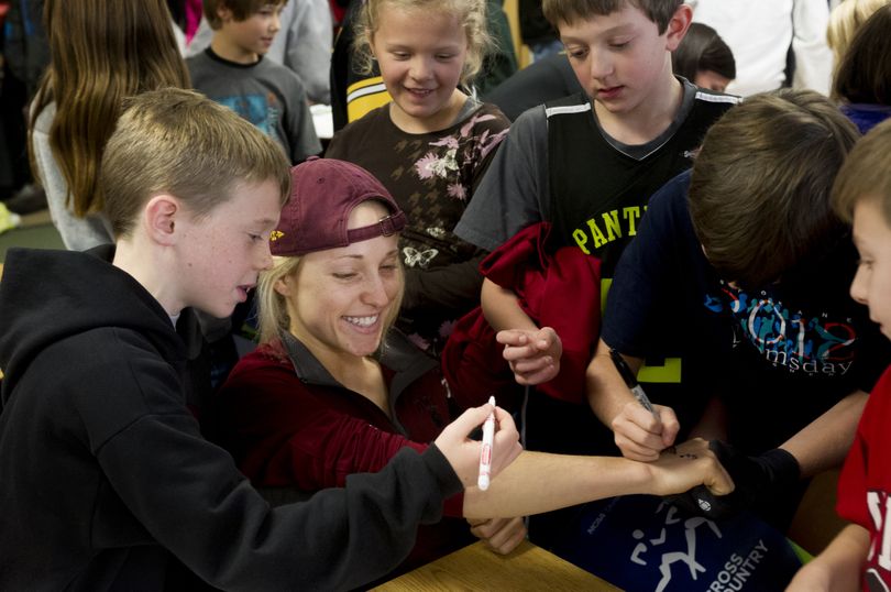 A group of middle schoolers sign University of Minnesota Duluth cross country runner Sam River’s arm after she signed notebooks and posters for them on Thursday at Pasadena Park Elementary School in Spokane Valley. (Tyler Tjomsland)