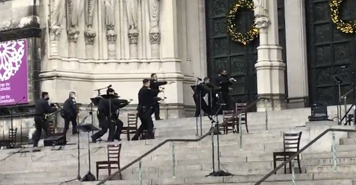 New York police officers move in on the scene of a shooting at the Cathedral Church of St. John the Divine, Sunday, Dec. 13, 2020, in New York. A man was shot by police after shots rang out at the end of a Christmas choral concert on the steps of the Manhattan cathedral Sunday afternoon. It