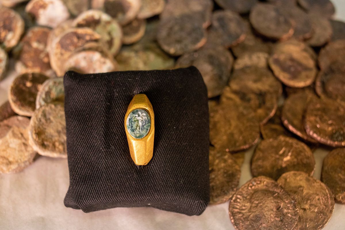 Roman gold ring, its green gemstone carved with the figure of a shepherd carrying a sheep on his shoulders is on display with coins that where found near the ancient city of Caesarea, dated to the Roman and Mamluk periods, around 1,700 and 600 years ago, in Jerusalem, Wednesday, Dec. 22, 2021. The Israel Antiquities Authority says it discovered the remnants of two shipwrecks off the Mediterranean coast replete with a sunken trove of hundreds of silver and bronze coins and Roman and medieval artifacts. "The image, of the 
