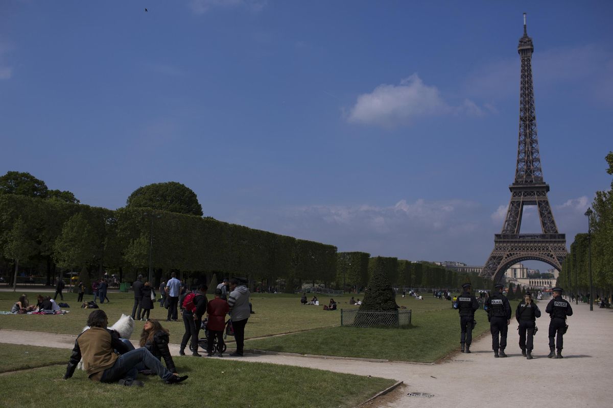 French police officers patrol with the Eiffel Tower in background, in Paris, Saturday, April 22, 2017. The outcome of France