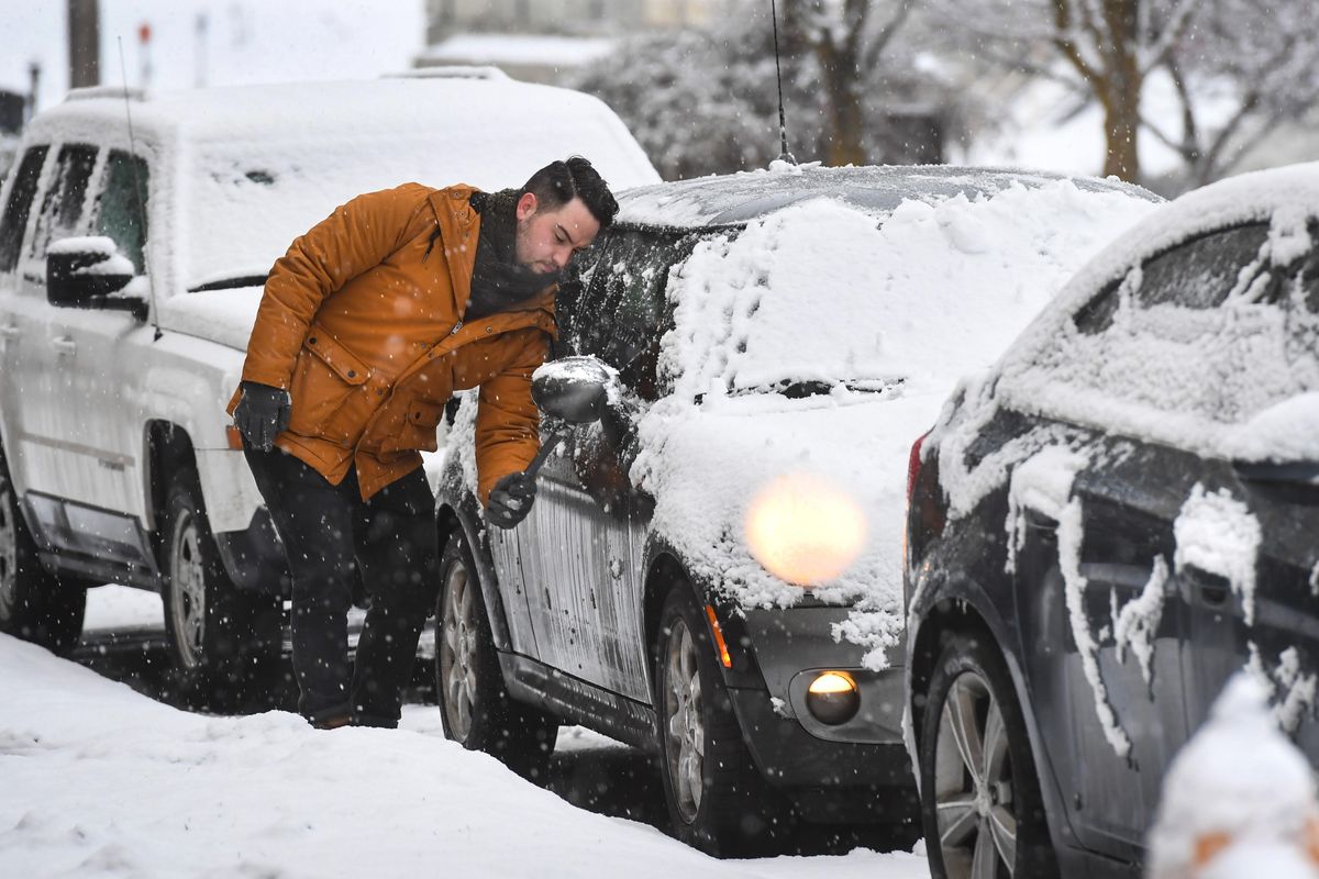 Scott Weller, 26, of Spokane, hopes he was is clearing snow off his 2007 Mini Cooper for the  final time this season after heavy, wet snow fell over the area, Tuesday, March 12, 2019, in Spokane. Weller was on his way to work from the Browne’s Addition neighborhood. (Dan Pelle / The Spokesman-Review)