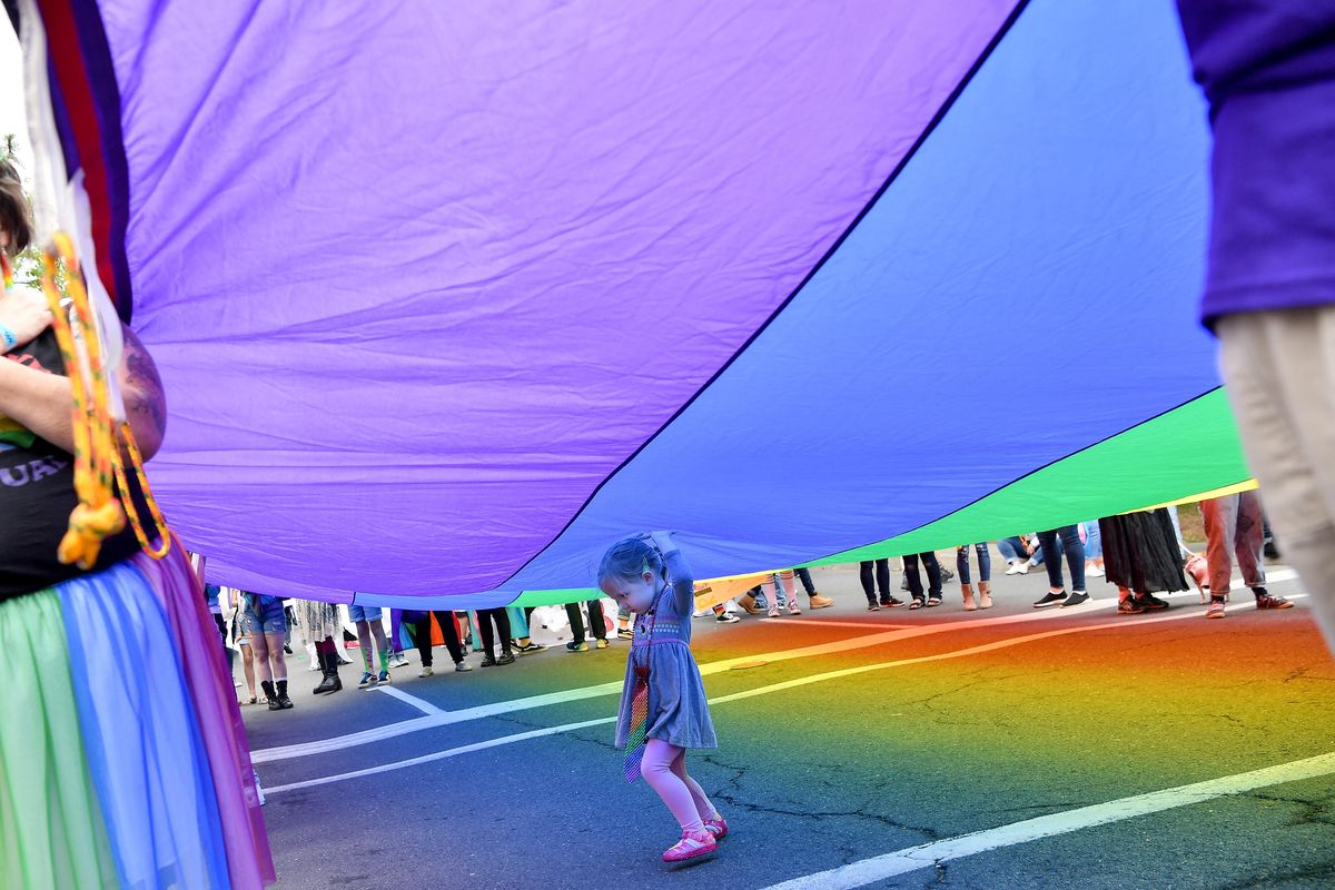 Allie Weeks runs her hands over a giant pride flag as she waits with her mother Carie for the 2019 Spokane Pride Parade to begin Saturday. (Tyler Tjomsland / The Spokesman-Review)