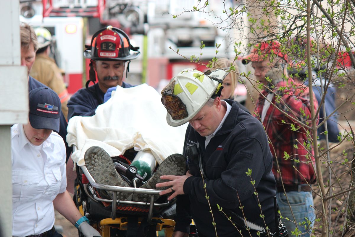 Spokane firefighters bring 29-year-old Nick Apperson out of a construction site after he apparently suffered a seizure and fell from a ladder. The fire department used a truck ladder like a crane to hoist him from inside 12-foot walls. (Jennifer Pignolet)