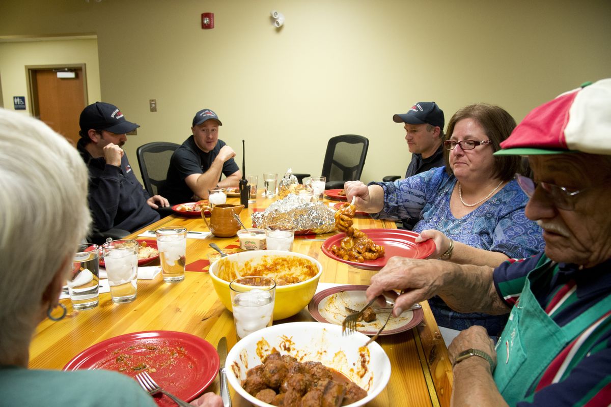 Mike Polignoni, right, and his daughter Alice Polignoni, second from right, serve up homemade gnocchi for the firefighters gathered at the dinner table on Nov. 10 at the Spokane Valley Fire Station 1. (Jesse Tinsley)
