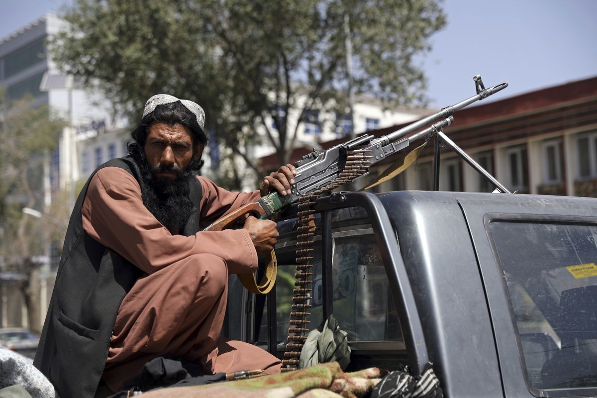 A Taliban fighter sits on the back of a vehicle with a machine gun in front of the main gate leading to the Afghan presidential palace, in Kabul, Afghanistan, on Monday.  (Rahmat Gul)
