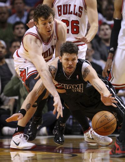 Chicago Bulls center Omer Asik, left, and Miami Heat guard Mike Miller scramble for a loose ball in the second half of a tight game. (Associated Press)