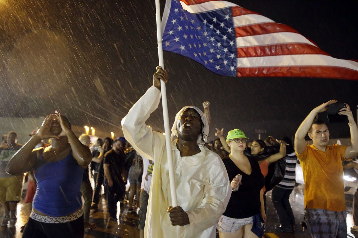 Protesters march in the rain, Sunday in Ferguson, Mo. Sunday marked one year since Michael Brown was shot and killed by Ferguson police Officer Darren Wilson. (Associated Press)