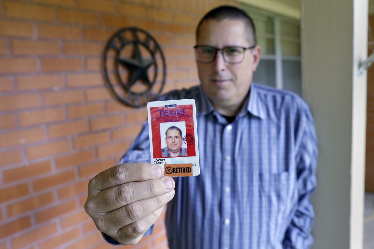 Lance Lowry, a recently retired corrections officer with the Texas State Penitentiary, holds his ID badge on the front porch of his home, Oct. 27, 2021, in Huntsville, Texas. Lowry, an officer for 20 years, became disheartened watching friends and coworkers die from COVID-19, along with dwindling support from his superiors. He left the prison system this summer for a job in long-haul trucking.  (Michael Wyke)