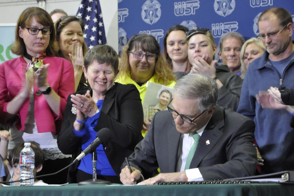 TACOMA – Spokane Valley resident Lavera Wade can’t contain her happiness while standing next to Gov. Jay Inslee as he signs a bill allowing police to ticket drivers using their smart phones for talking, texting or being on the Internet. Wade and other family members who lost loved ones in distracted driving accidents attended the signing ceremony Tuesday. (Jim Camden / The Spokesman-Review)