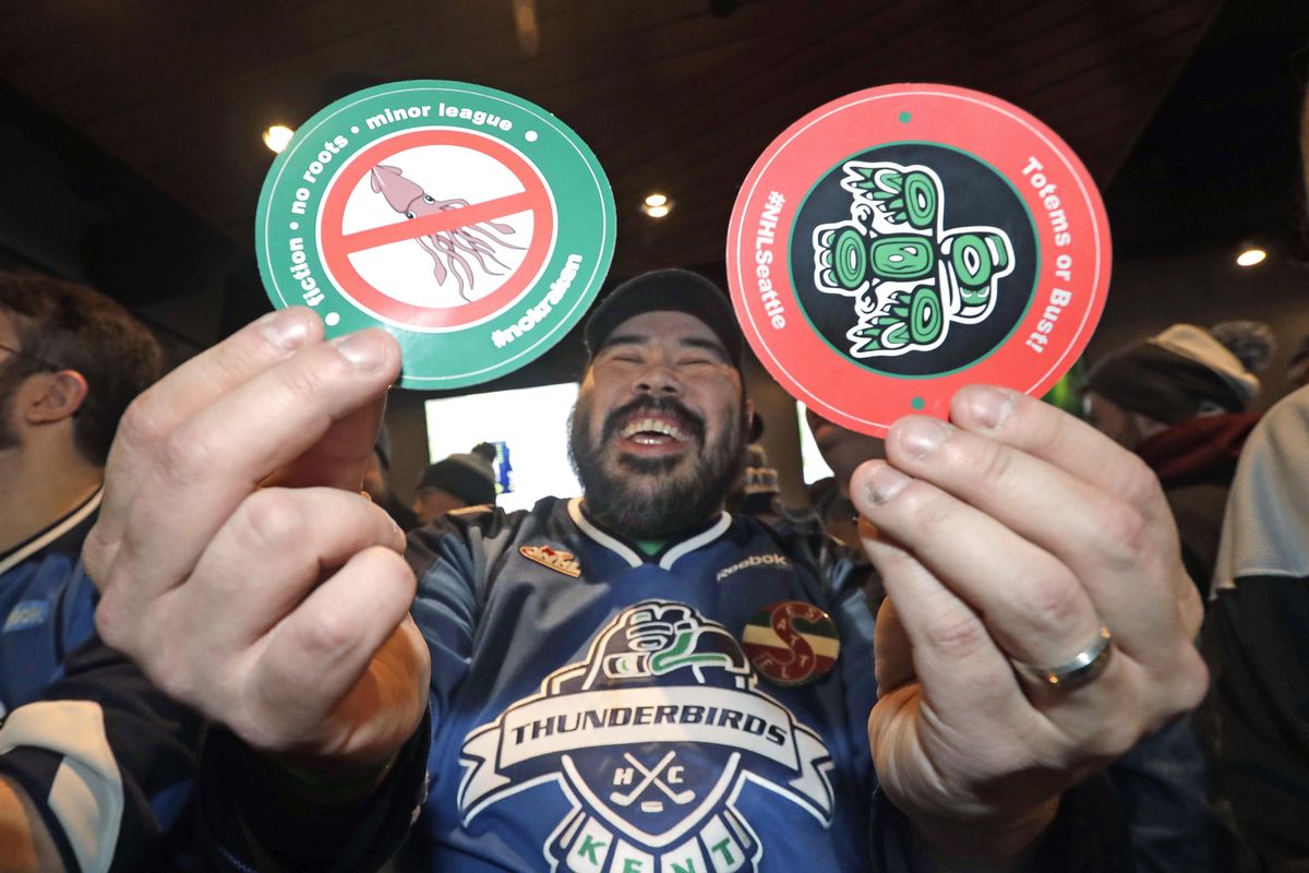 Otto Rogers playfully holds up stickers against the proposed name Kraken and in support of Totems following the announcement of a new NHL hockey team in Seattle, at a celebratory party Tuesday, Dec. 4, 2018, in Seattle. (Elaine Thompson / Associated Press)