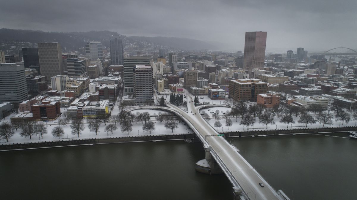 An aerial view of the Morrison Bridge and downtown Portland, Ore., is seen during a snowstorm, on Friday, Feb. 12, 2021. A winter storm has blanketed the Pacific Northwest with ice and snow, leaving hundreds of thousands of people without power and disrupting travel across the region.  (Brooke Herbert)