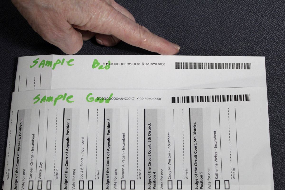 An election worker at the Clackamas County Elections office shows barcodes on ballots that are bad, top, and good on Thursday in Oregon City, Ore. Ballots with blurry barcodes that can’t be read by vote-counting machines will delay election results by weeks in a key U.S. House race in Oregon’s primary.  (Gillian Flaccus)