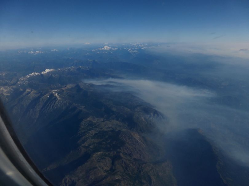 While Glacier Peak and Mount Baker poke up into blue skies on the morning of Aug. 5, 2014, smoke from the Carlton Complex wildfires in the Methow Valley and newer fires near Leavenworth spew smoke that spreads across northeastern Washington. (Rich Landers)
