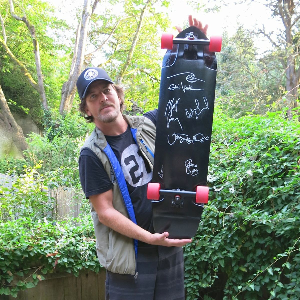 Eddie Vedder poses with a longboard he and band members from Pearl Jam signed for an auction to benefit the Ferry County Rail Trail. (Bob Whittaker)