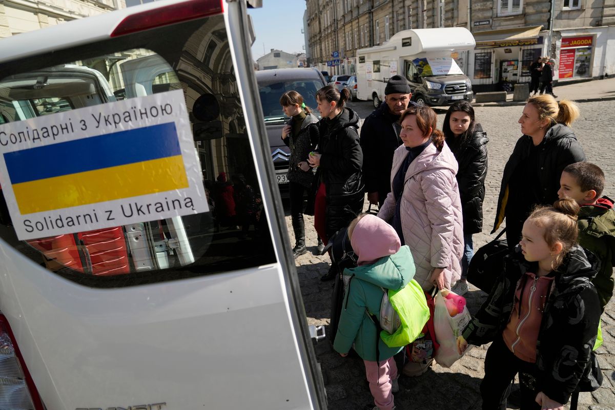 Ukrainian refugees with children board transport at a square next to a railway station in Przemysl, Poland, on Tuesday, March 22, 2022.  (Sergei Grits)