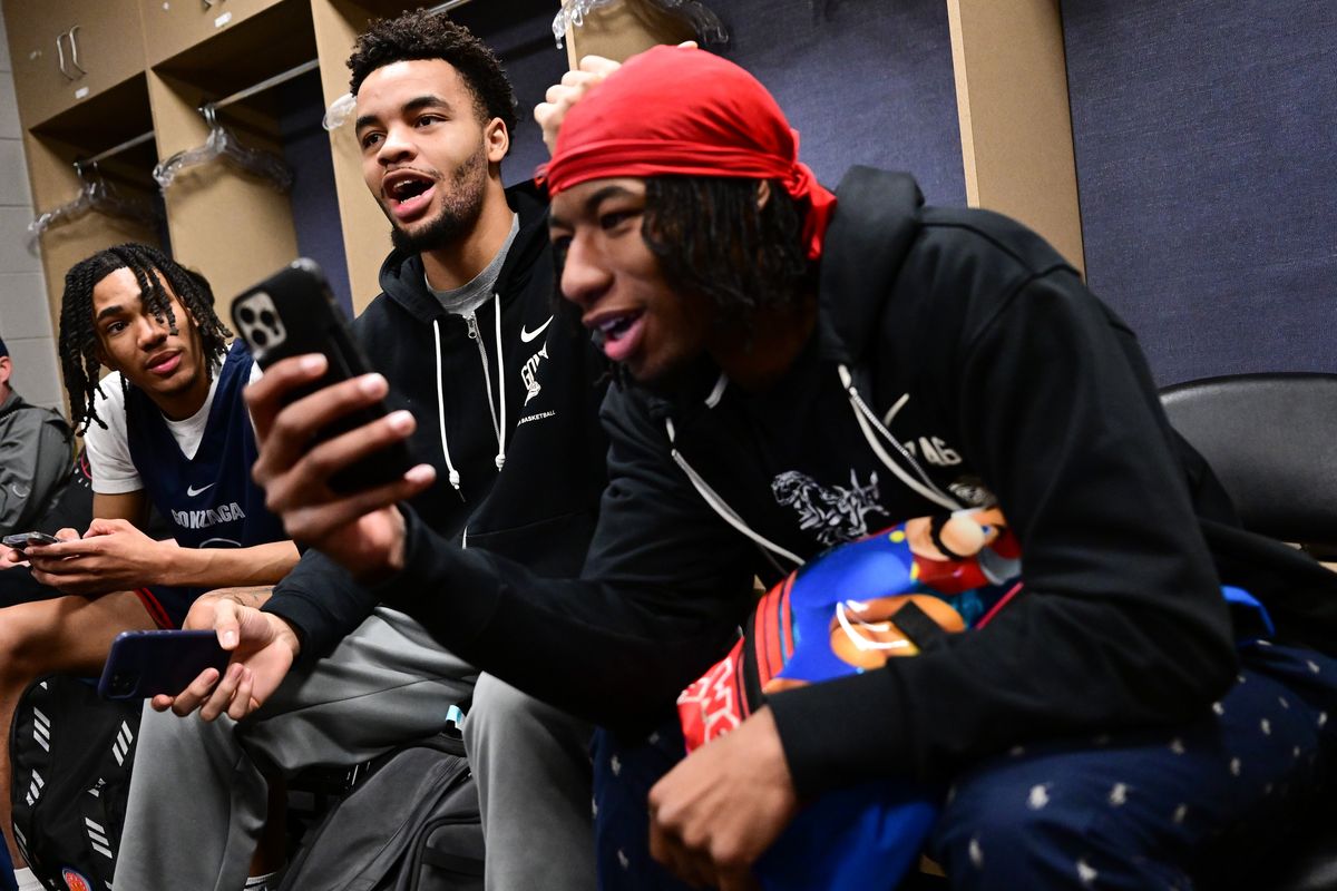 From left, Gonzaga guard Hunter Sallis laughs with forward Colby Brooks and guard Dominick Harris, while checking phones at a locker room media session Saturday.  (By Tyler Tjomsland/The Spokesman-Review)