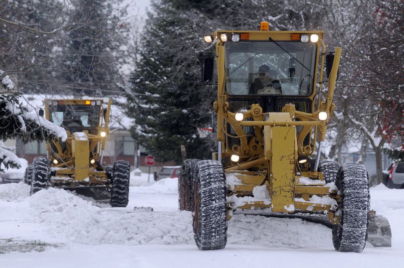 Two contracted graders clear compact snow and ice off 15th Avenue just east of McDonald Road in Spokane Valley on Monday.  (J. Bart Rayniak)