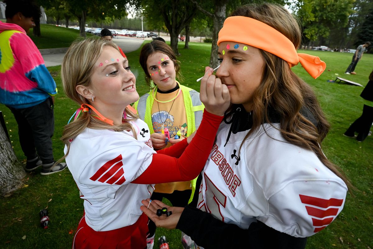 For their homecoming game, Riverside cheerleader Caitlyn Potter paints neon dots on Olivia Oergel before their football game Friday night with Medical Lake. Emma Oergel, in back, watches.  (COLIN MULVANY/THE SPOKESMAN-REVIEW)
