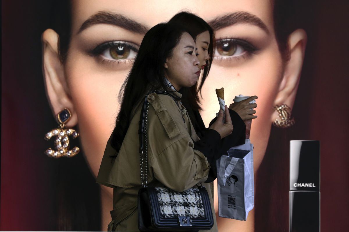 Women eating snack walk Oct. 19, 2020, past a Chanel cosmetic shop at the capital city