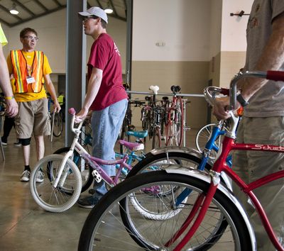 Chad Cleaver, center, checks in his children’s used bikes with the Spokane Bike Swap and Expo’s Tomas Lynch, left, April 10, 2015, at the Spokane County Fair & Expo Center. (Dan Pelle / The Spokesman-Review)