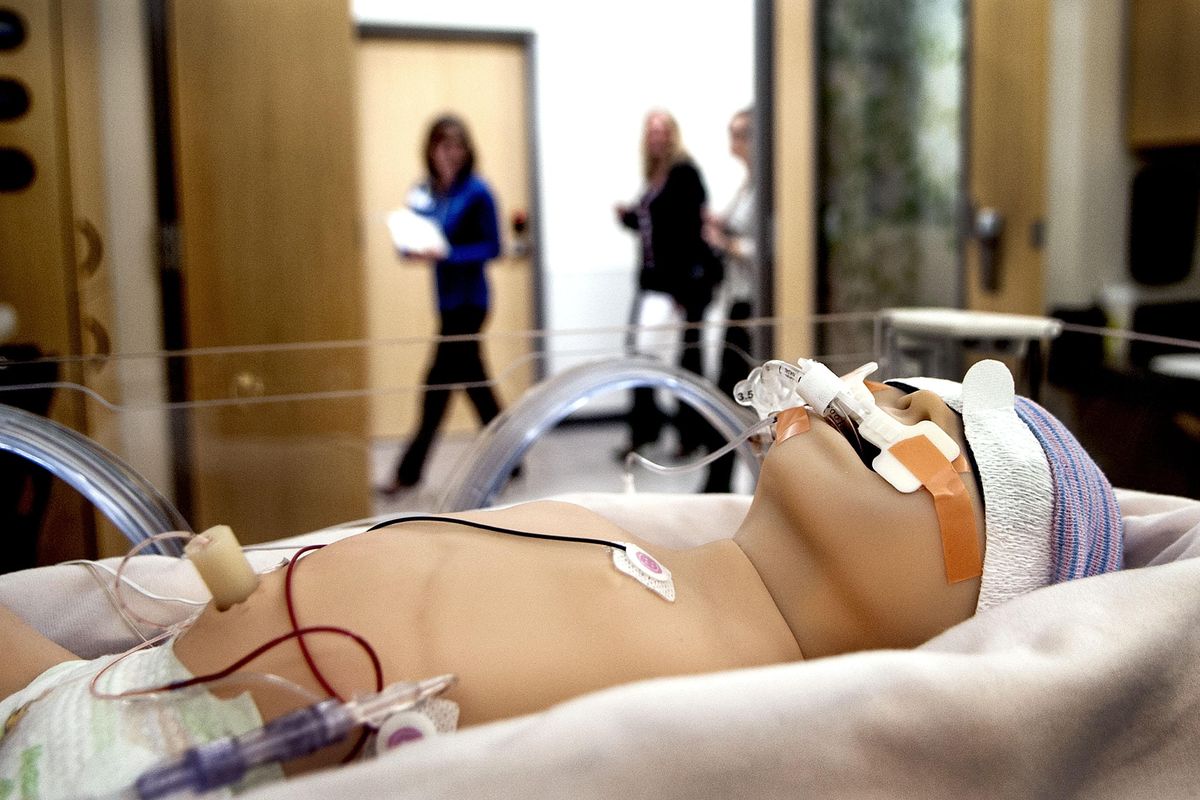 A tour guide leads a group past the expanded neonatal intensive care unit in Kootenai Health’s $57 million east addition in Coeur d’Alene on Thursday. Dolls were used to show how the equipment would be used when the new family birth center opens this month. (Kathy Plonka / The Spokesman-Review)