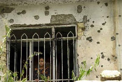 
An Iraqi girl looks out a window in a wall covered with bullet holes in the village of Buhriz, near Baqouba, on Sunday. 
 (Associated Press / The Spokesman-Review)