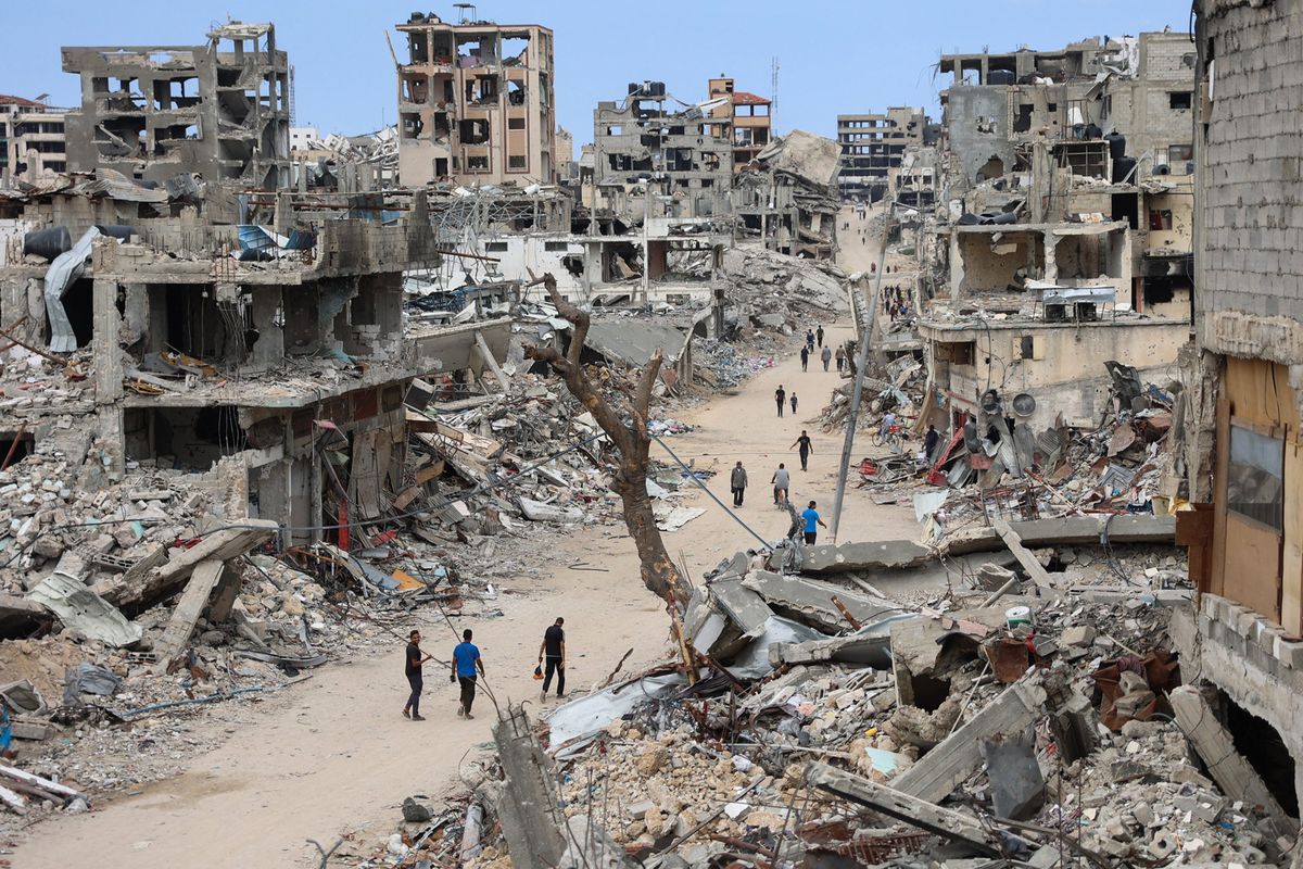 Palestinians walk on a dirt road lined with building rubble in the Shujaiya neighborhood of Gaza City on Oct. 7, 2024, on the first anniversary of the ongoing war in the Gaza Strip between Israel and the Palestinian Hamas group. (Omar Al-Qattaa/AFP/Getty Images/TNS)  (Omar Al-Qattaa/AFP)