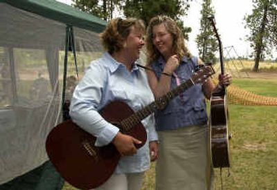Sisters Holly Fletcher and Jeannie McCullough share a laugh before performing at the Blue Waters Bluegrass Festival at Waterfront Park in Medical Lake on Sunday. The sisters plus their other three siblings, Connie Fletcher, Brenda Hanson and Kelli Medhus make up the Fletcher Girls. 
 (Liz Kishimoto / The Spokesman-Review)