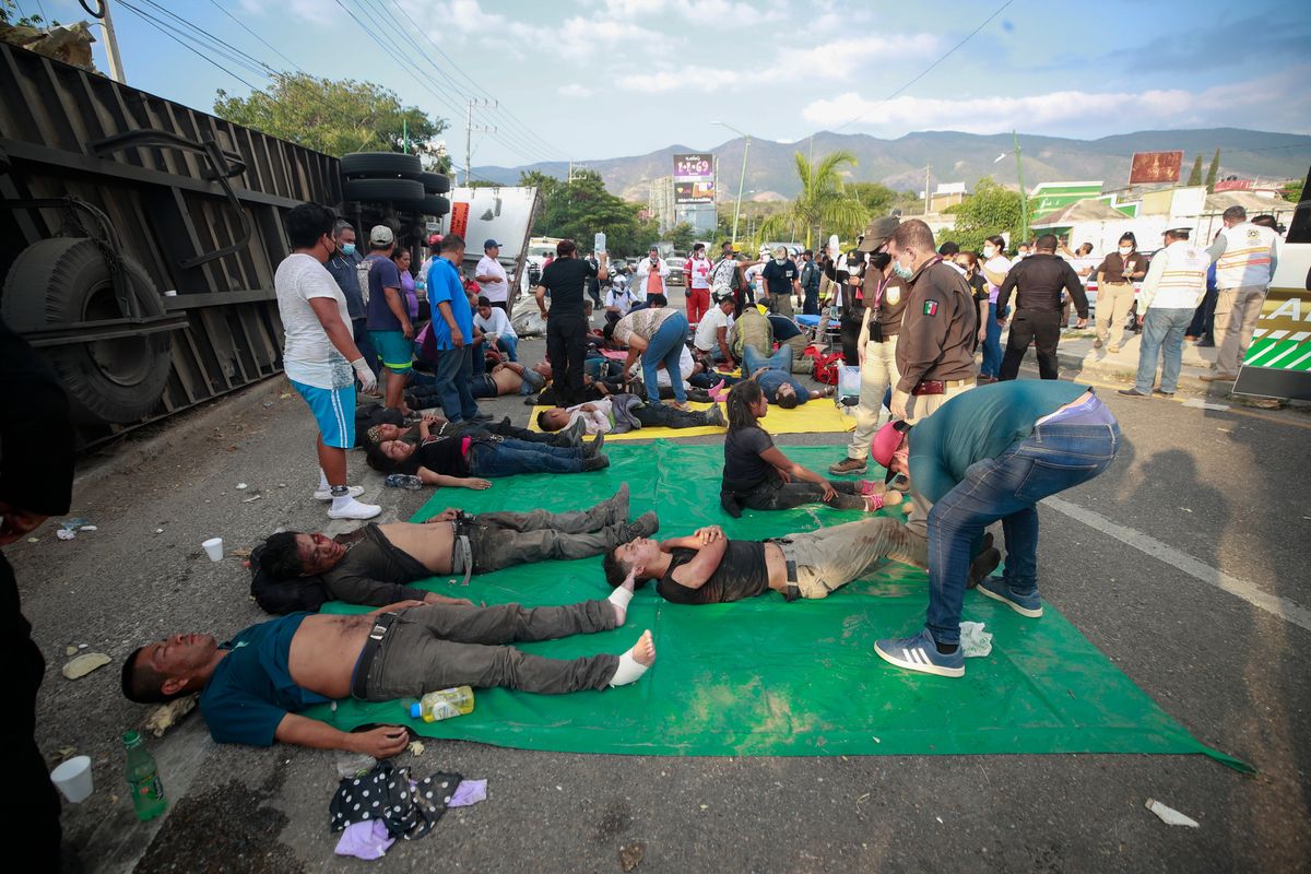 Injured migrants are cared for on the side of the road next to the overturned truck on which they were traveling near Tuxtla Gutierrez, Chiapas state, Mexico, Dec. 9, 2021. Mexican authorities say at least 49 people were killed and dozens more injured when the truck carrying the migrants rolled over on the highway in southern Mexico.  (STR)